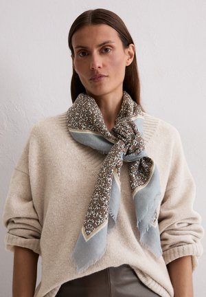 Écharpe marron et bleue avec un motif floral, bordée d'une bordure beige. Tissu doux aux bords effilochés, enroulée autour du cou.