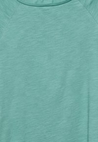 Vaalean teal, teksturoitu kangas heather-mallilla; sisältää pyöreän kaula-aukon ja raglan-hihat rentoa istuvuutta varten.