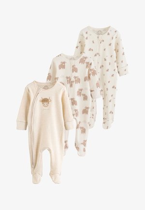Tre beige babysoveraller med fødder; den ene har et lille koansigt og tekst, de to andre har brune ko-mønstre over det hele.