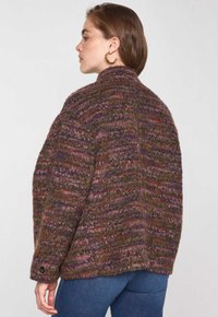 Veste en laine multicolore avec un col haut, présentant un motif texturé dans des teintes de violet, vert et rouille, et un détail de bouton au niveau des poignets.