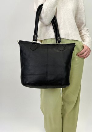 Schwarze Leder-Tote mit zwei stabilen Griffen, einer glatten Textur und dreieckigen Lederakzenten in der Nähe des Saums. Geräumiges und strukturiertes Design.