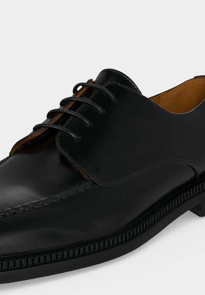 Μαύρο δερμάτινο επίσημο παπούτσι με κορδόνια, λεία επιφάνεια, στρογγυλεμένη μύτη και καφέ εσωτερική επένδυση, εμφανιζόμενο από πλάγια γωνιακή όψη.