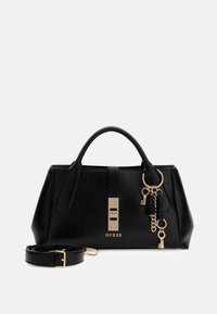 Czarna skórzana torebka o strukturalnym kształcie, z akcentami w kolorze złotym i detalami łańcuszka. Zawiera odpinany pasek. Logo "GUESS" z przodu.