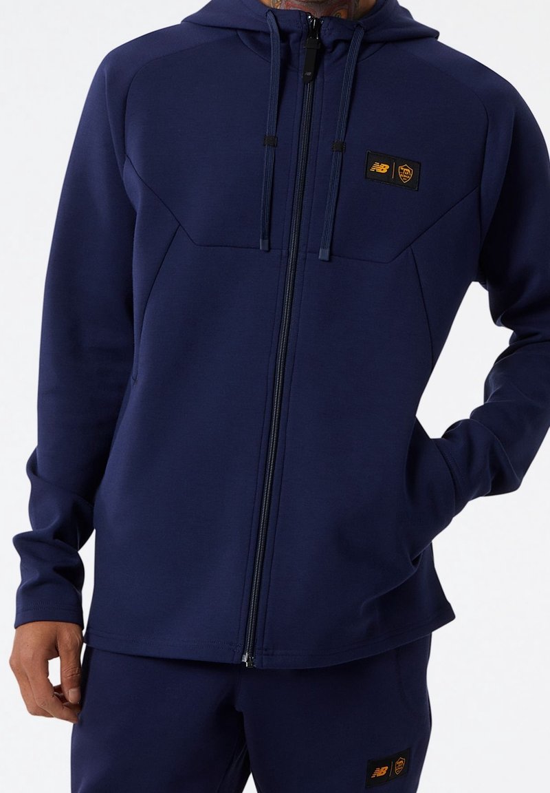 Felpa con zip navy realizzata in materiale morbido, con cappuccio, tasche frontali e toppe con logo a contrasto sul petto e sulle maniche.