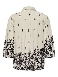 Blouse crème avec motifs floraux et feuilles noires, manches 3/4 et col, vue de dos.