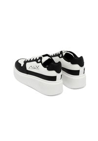 Zwart-witte chunky sneakers met een glad leren bovenwerk, vetersluiting en een dikke witte plateauzool. Merklogo aan de zijkant.