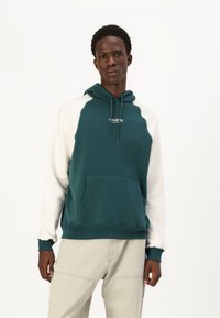 Hooded sweatshirt with teal body and white sleeves. Features a front pocket, adjustable drawstring, and embroidered logo on the chest.