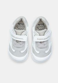 White and gray sneakers with a mesh upper, suede accents, and a Velcro strap. Rounded toe and textured rubber sole for grip.