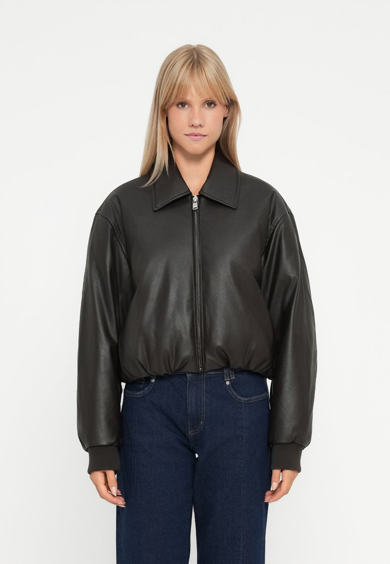 Veste bomber en cuir noir avec un grand col, fermeture éclair et poignets côtelés. Légère et ajustée avec un ourlet arrondi.