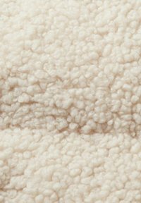 Crèmekleurige, pluchen stof met een gestructureerd, lusvormig oppervlak en een zachte, donzige uitstraling. Ideaal voor warmte en comfort.