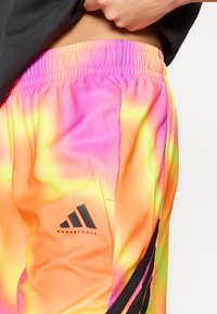Μπασκετικά σορτς σε διαβαθμισμένα νέον χρώματα, με αποχρώσεις μωβ, ρόζ και πορτοκαλί. Μαύρο λογότυπο Adidas και απαλό, ελαφρύ ύφασμα.