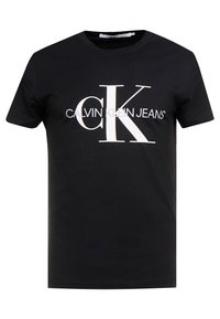 Svart bomullströja med en framträdande vit logga med 'CK' och texten 'CALVIN KLEIN JEANS'. Standard rundad hals och korta ärmar.