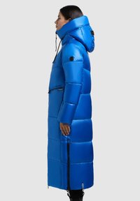Langer Puffermantel in leuchtendem Blau, mit hohem Kragen, Kapuze, horizontaler Steppung, Reißverschlusstaschen und schwarzen Akzenten an den Ärmeln.