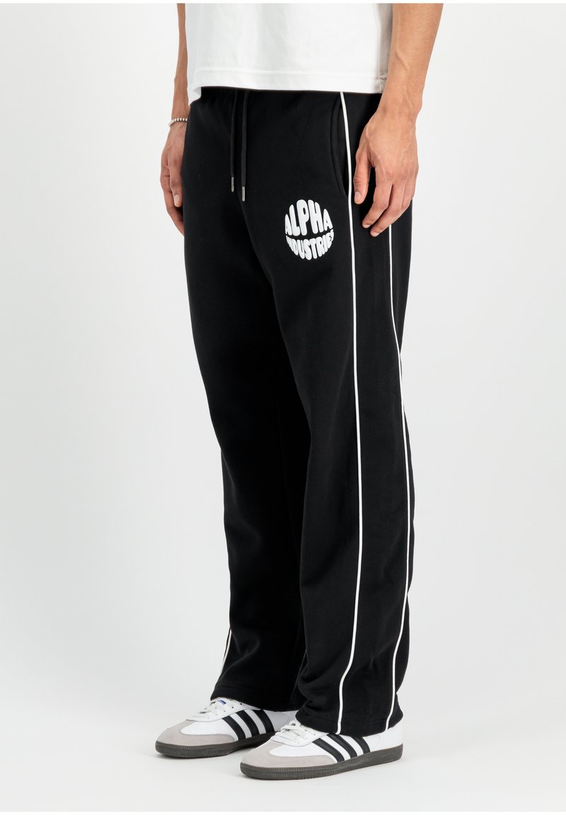 Schwarze Sweatpants mit weißen Seitenstreifen und dem Logo 'ALPHA INDUSTRIES'. Hergestellt aus weichem Stoff, mit elastischem Bund und Kordelzug.