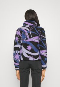 Zwarte en paarse fleece jas met een hoge kraag, voorzien van sterpatronen en spiralen, die een gedurfde grafische uitstraling heeft.