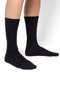 Calcetines de algodón negros con un puño acanalado, de longitud a medio pantorrilla, textura suave y sin patrones visibles ni detalles de hardware.