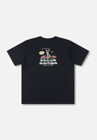 T-shirt preta de algodão com um design gráfico colorido nas costas, apresentando uma figura de desenho animado e flores, com o texto "Rivvia Projects" abaixo.
