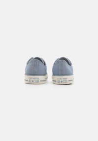 Világoskék vászon tornacipő alacsony felsőrésszel. Fehér gumitalp "CONVERSE ALL STAR" felirattal. Texturált varrás a saroknál.