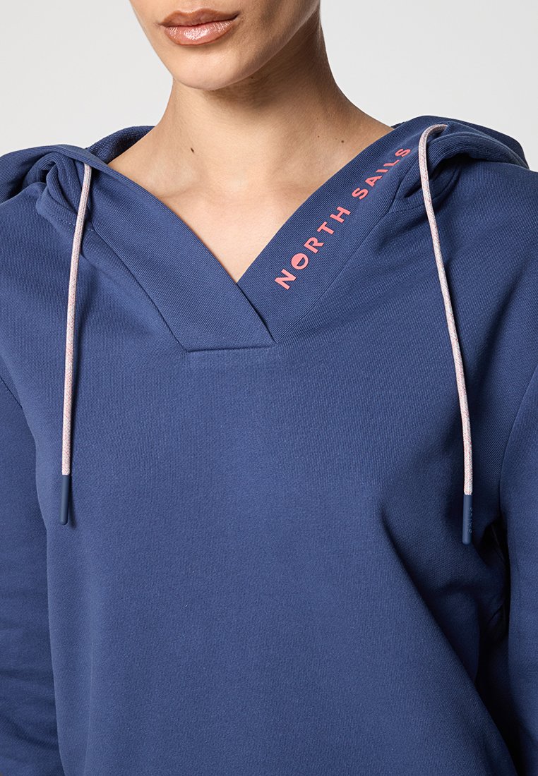 Dunkelblauer Hoodie mit V-Ausschnitt, pinken Kordelzügen und dem Logo "NORTH SAILS" am Kragen. Glatte Textur des Stoffes.