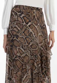 Gonna a stampa serpente marrone con orlo arricciato, texture a strati e vita elastica per una vestibilità comoda. Tessuto leggero e morbido.