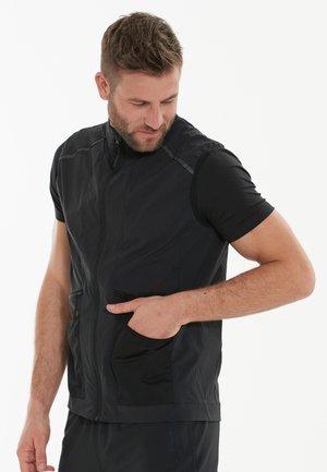 Zwarte mouwloze vest met een rits aan de voorkant, twee zijzakken en een lichtgewicht stof met een soepele textuur.