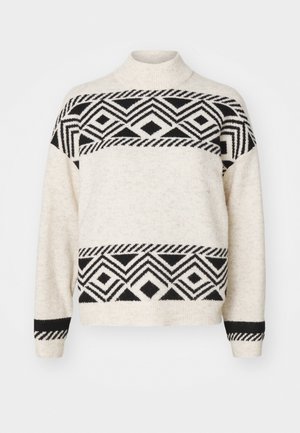 Krém színű kötött pulóver, fekete geometrikus mintákkal, magas nyakkal és bordás mandzsettákkal. Puha textúra, kontrasztos fekete csíkokkal.