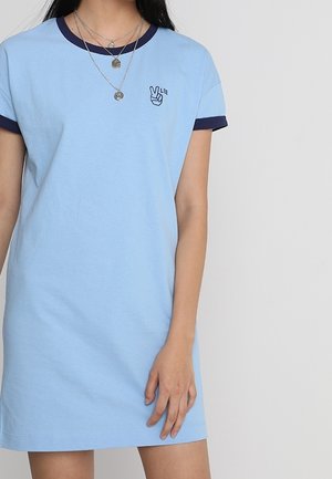 Hellblaues Baumwoll-T-Shirt-Kleid mit kurzen Ärmeln und einem marineblauen gerippten Kragen. Mit einem kleinen gedruckten Friedenzeichen auf der Brust.