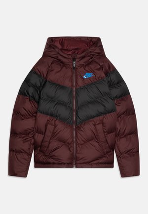Nike pufferjack met een bordeauxrode en zwarte chevrondesign, voorzien van een ritssluiting aan de voorkant, een capuchon en een blauw logo op de borst.