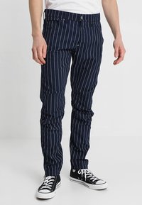 Marinblårandiga byxor i en bomullsblandning, med smal passform, bälteshällor, fram- och bakfickor samt knappstängning.