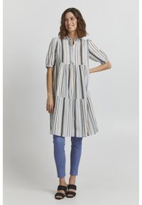 Abito tunica a righe di lunghezza ginocchio in blu chiaro, blu navy e arancione. Maniche corte e placket con bottoni dal design a strati. Abbinato a pantaloni blu chiaro.