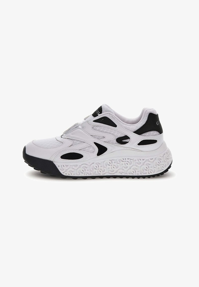 Sneaker atletica bianca e nera con tomaia in rete, accenti neri decorativi e suola patterned con forme interconnesse in rilievo.