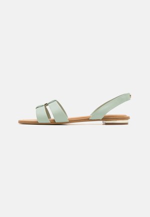 Mintgrønne flade sandaler med to brede stropper, et slingback-design, en naturlig træsål og en guldfarvet detalje på hælen.