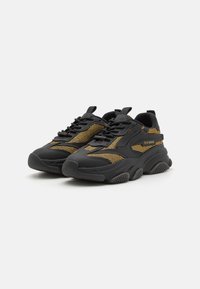 Zapatillas chunky negras con detalles de malla, acentos dorados y suelas de goma. Cuenta con cordones y bucles para facilitar su puesta.