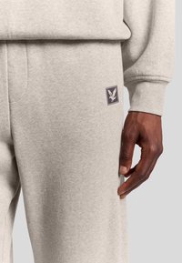 Pantaloni grigi in felpa di cotone, con un piccolo logo viola ricamato, tasche laterali e un design a vestibilità rilassata.