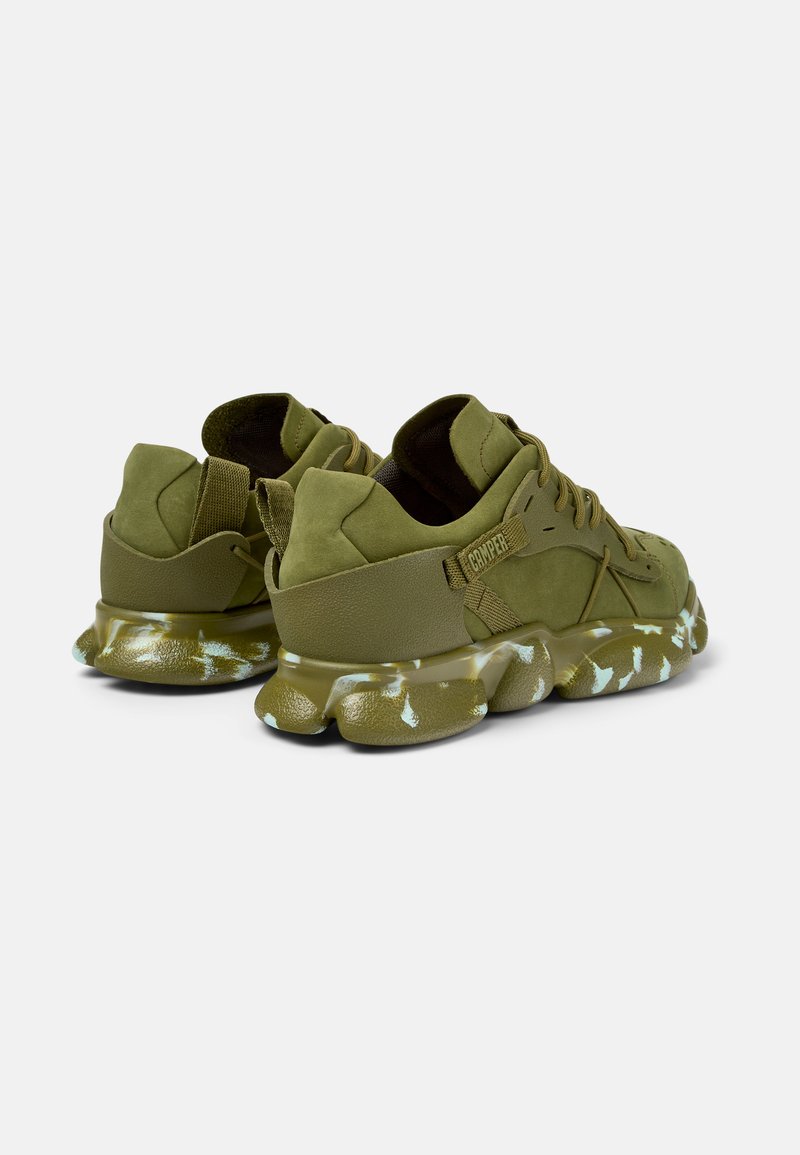 Grüne Wildleder-Sneaker mit einem strukturierten Fersenbereich und einer gemusterten Sohle mit weißen Akzenten. Enthält Schnürsenkel und eine Schlaufe an der Rückseite.