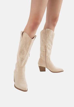 Botas de vaquero de ante beige hasta la rodilla con intrincadas cuentas plateadas y puntera puntiaguda, que cuentan con una cremallera y detalles de tacón apilado.
