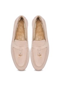 Mocassini color beige chiaro in pelle liscia, dotati di una morbida fodera in pelliccia, cuciture decorative e un sottile accento dorato sul davanti.