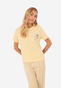 T-shirt di cotone gialla con maniche corte, con un design grafico di un limone e un personaggio carino sul petto sinistro.
