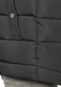 Schwarze Steppjacke mit einem gesteppten Design, bestehend aus horizontalen Abschnitten, einer Seitentasche und einem braunen Knopfdetail. Glattes, leicht glänzendes Material.