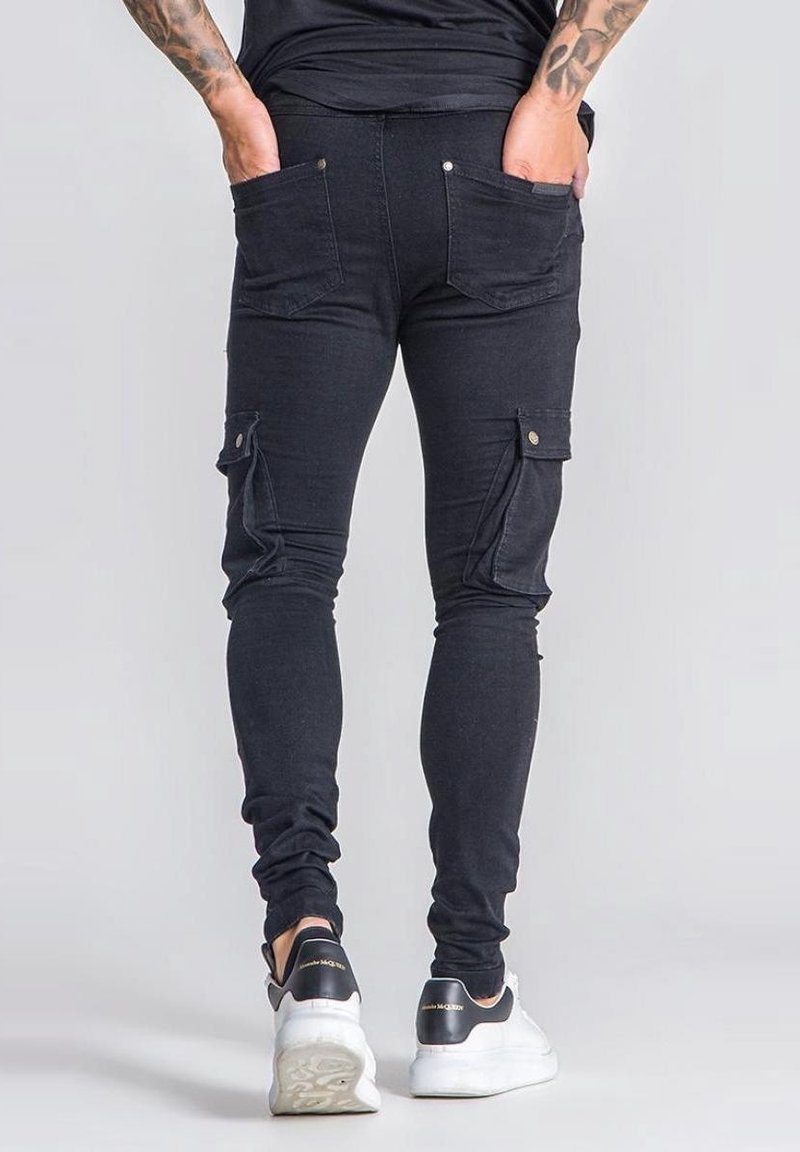 Pantalones cargo de mezclilla negra con corte ajustado, bolsillos laterales tipo cargo y bolsillos traseros de parche. Estilizados con una cinturilla ajustada y un diseño de largo hasta el tobillo.