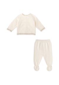 Conjunto de bebé color crema que incluye una camiseta de manga larga con puntos texturizados y un par de pantalones ajustados con pies redondeados. Material de punto suave.