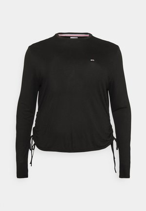 Chemise noire à manches longues avec col rond, petit logo sur la poitrine et liens latéraux réglables créant des fronces de chaque côté.