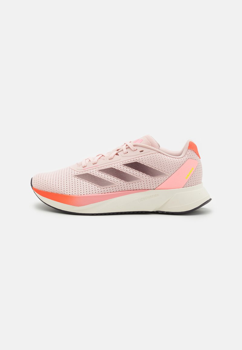 Scarpa da corsa leggera di colore rosa con tomaia in mesh, tre strisce scure e un sottopiede arancione sfumato. Presenta un colletto imbottito e lacci.