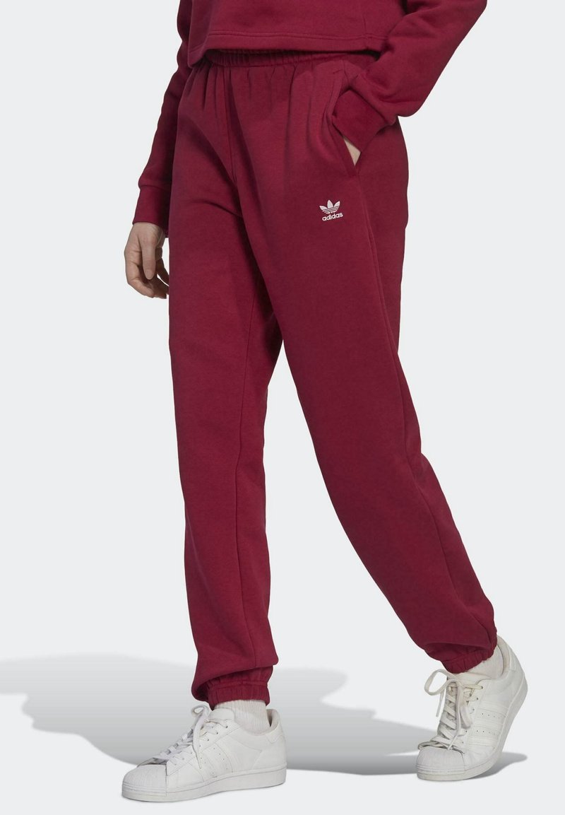 Burgunderfärgade sweatpants gjorda av mjukt tyg med elastisk midja och mudd. Har sidofickor och en vit Adidas-logga på höften.