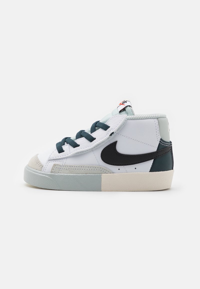 White and teal sneaker with black swoosh, rubber sole, padded collar, and textured toe cap. Features green laces and logo tag on tongue.