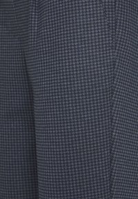 Tissu à motif pied-de-poule bleu marine avec une texture lisse, présentant un tissage subtil et des détails fins dans des tons de bleu clair.