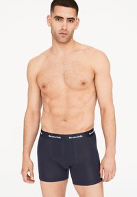 Tmavě modré boxerky vyrobené z měkké, elastické látky. Mají černý pas s bílým brandingem "Resteröds" a přiléhavý střih.