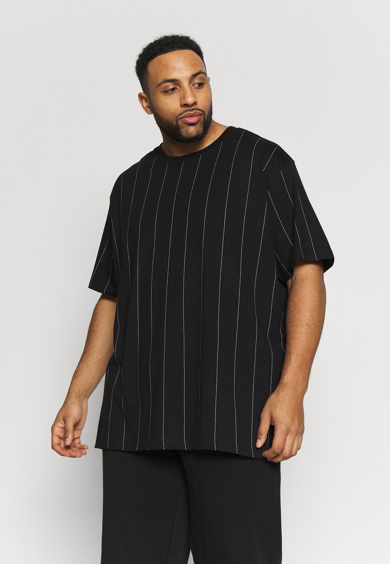 Chemise noire à manches courtes avec des rayures verticales blanches. La coupe décontractée et le tissu doux offrent un look casual.