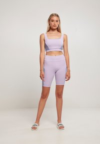 Lys lilla atletisk crop top og matchende høyt liv sykkelshorts, med figursydd design og kontrasterende sidepaneler.