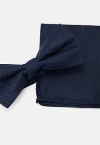 Ensemble cravate papillon et pochette de couleur bleu marine en tissu texturé, présentant un motif tissé avec des bords nets et une finition poli.